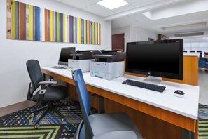 Un espacio de oficina moderno con un escritorio blanco, varias computadoras y un monitor grande.