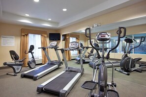 Un gimnasio con cintas de correr, bicicletas estáticas y una máquina elíptica.