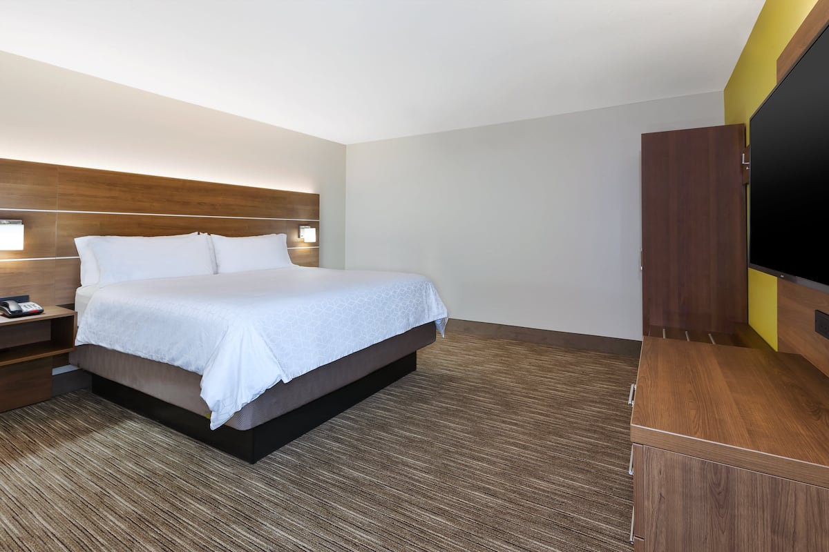 Ein Hotelzimmer mit Bett, Nachttisch, Lampe und Fernseher.