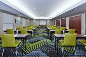 A conference room with tables, chairs, a projector screen, and a carpeted floor.