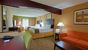 Quarto de hotel com cama, escrivaninha, cadeira, sofá e luminária.
