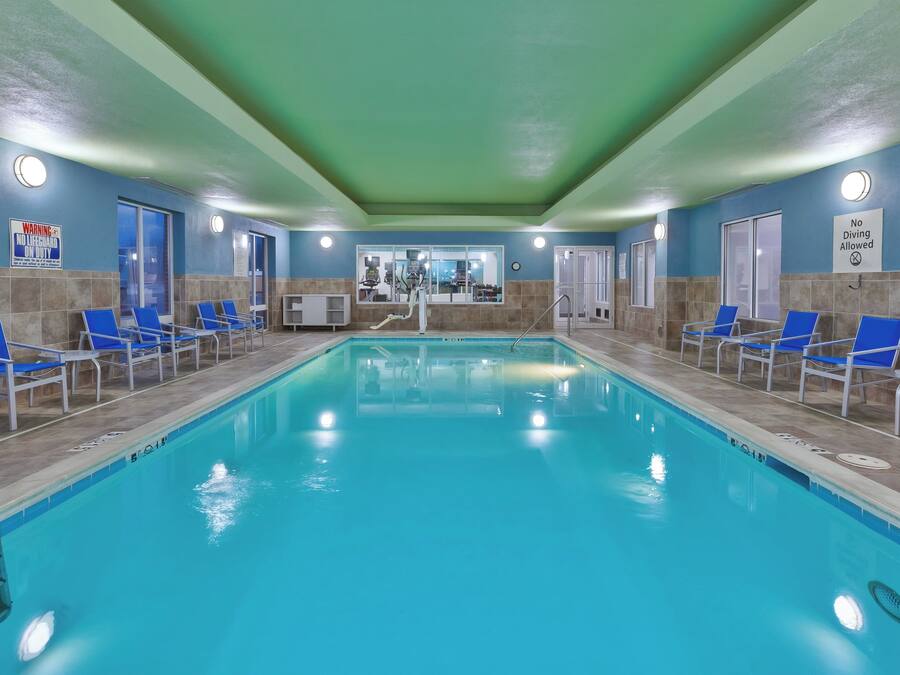 An indoor swimming pool with blue chairs and a no diving allowed sign.