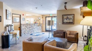 A lobby with a stone fireplace, leather seating, a trash can, and framed pictures on the walls. - Blue Mountain Inn And Suites (Rangely)