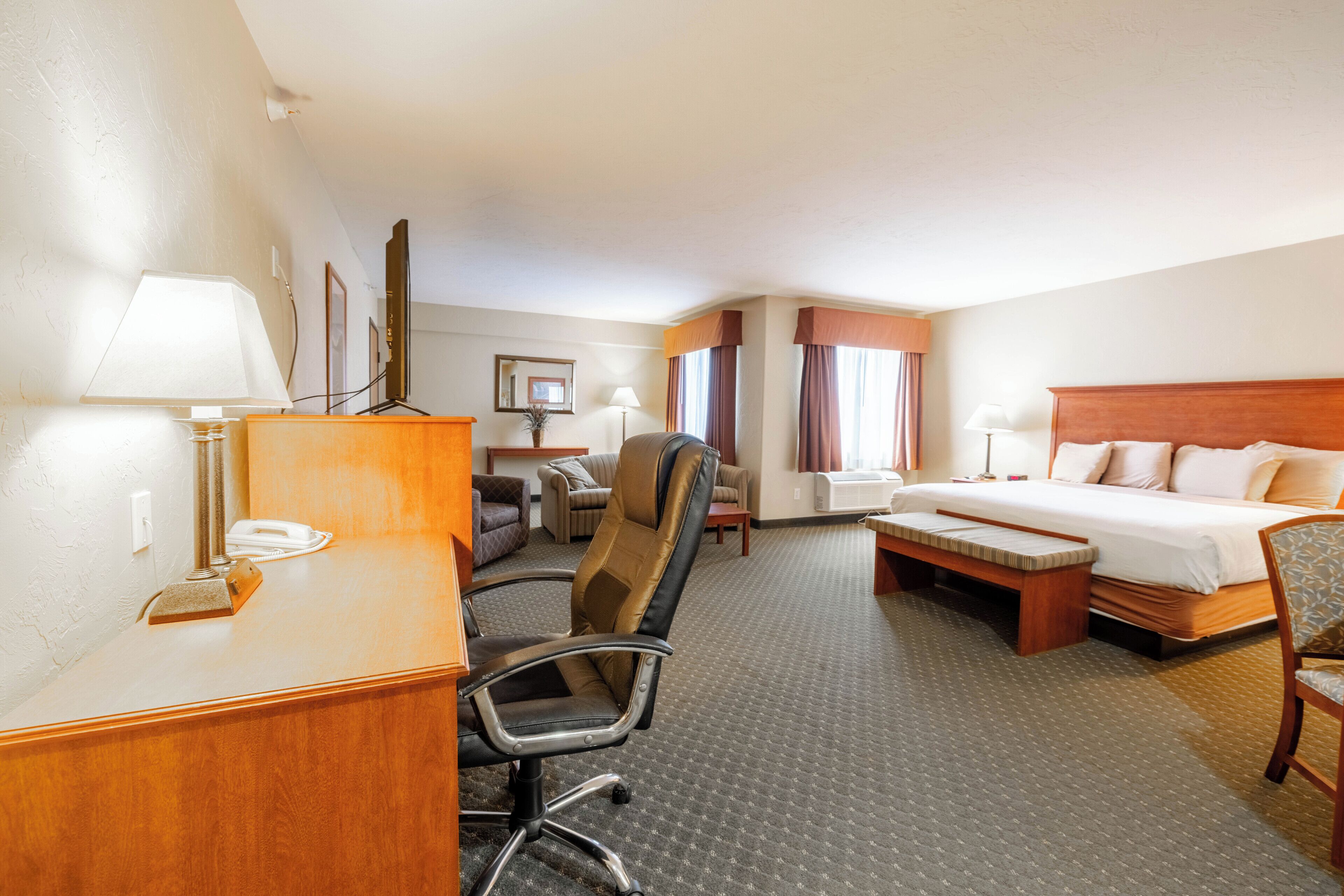Een hotelkamer met een bed, bureau, stoel en een klein tafeltje.