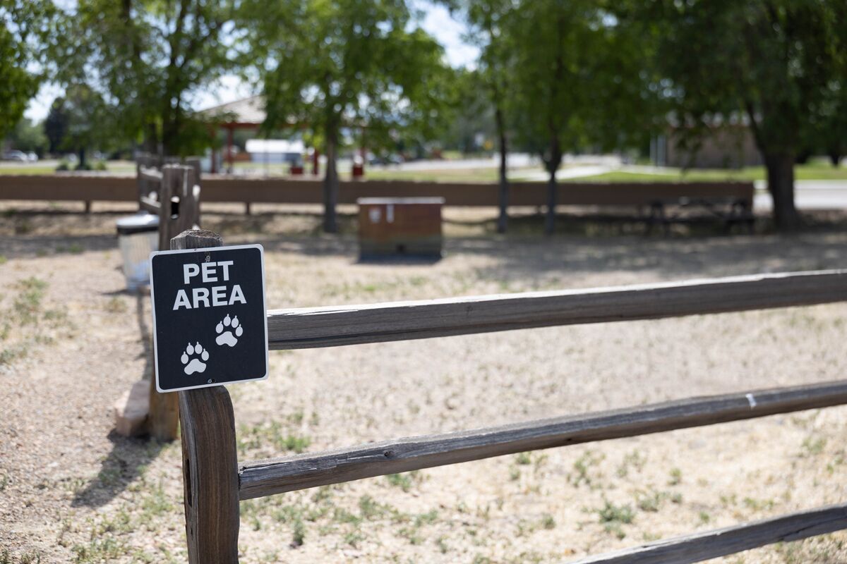A wooden bench with a sign indicating a pet area.