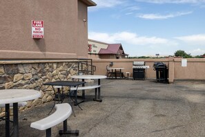 An outdoor patio with tables and a barbecue grill.