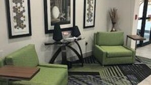 A modern living room with green sofas, a coffee table, and framed artwork on the wall.
