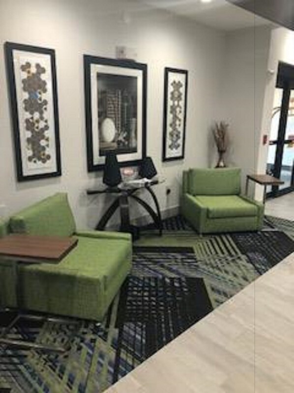Un salon moderne avec des canapés verts, une table basse et des œuvres d’art encadrées accrochées au mur.