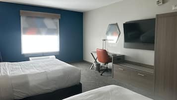 A hotel room with two beds, a desk, a chair, a TV, and a wardrobe.