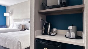 Ett hotellrum med två sängar, en minibar, en kaffebryggare och en mikrovågsugn.