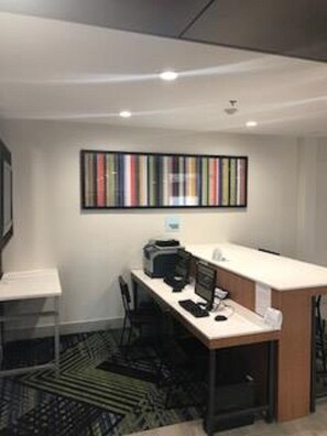 Un espace de bureau moderne avec un grand bureau, un ordinateur et une chaise. Un mur est orné d’une bibliothèque remplie de livres, et un tapis à motifs recouvre le sol.