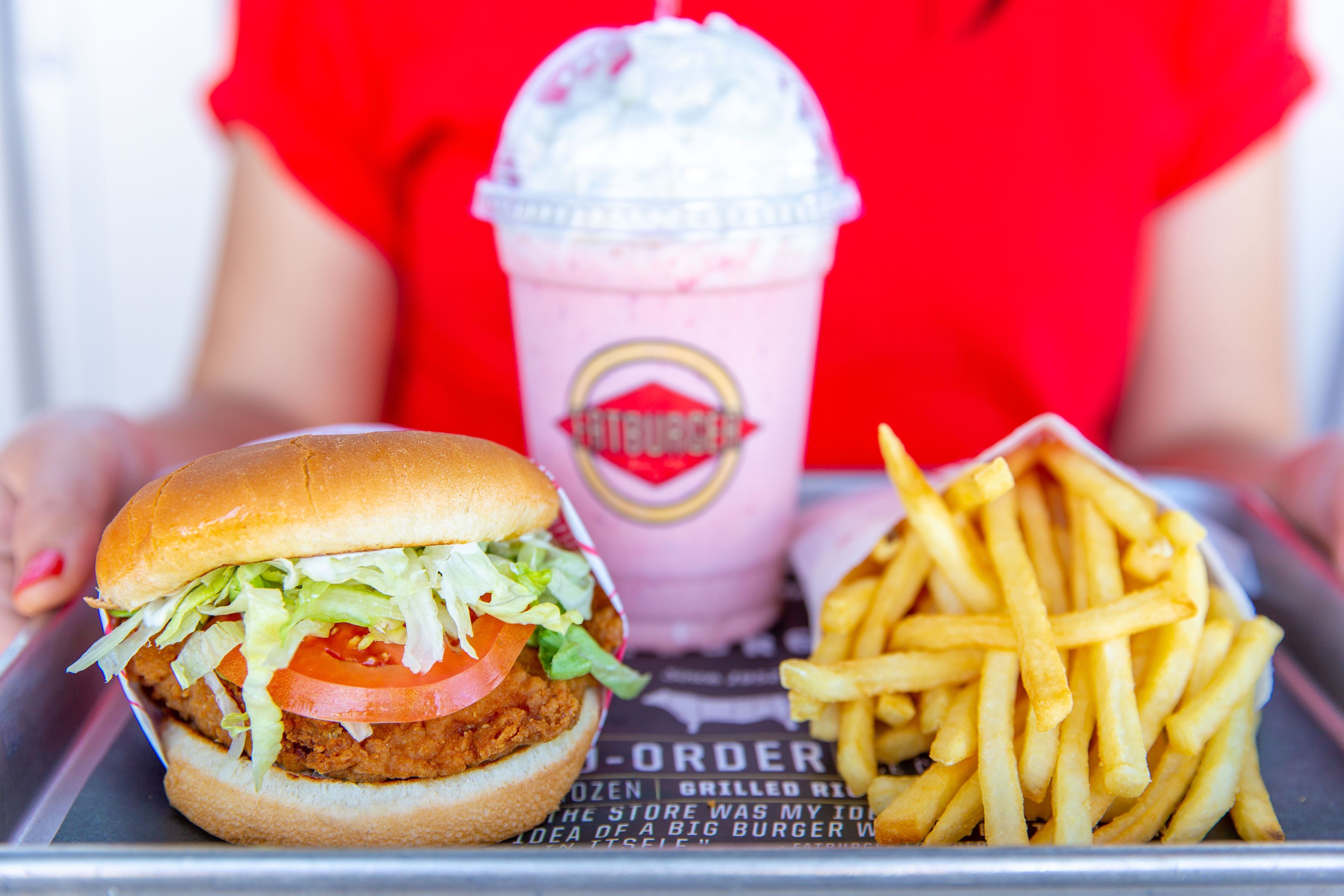 A meal consisting of a chicken burger, a soft drink, and French fries.
