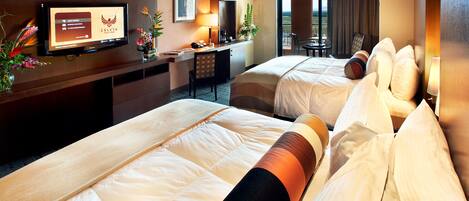 Ein Hotelzimmer mit zwei Betten, einem Schreibtisch mit Computer, einem Fernseher, der eine Webseite anzeigt, und einem Balkon mit Aussicht.