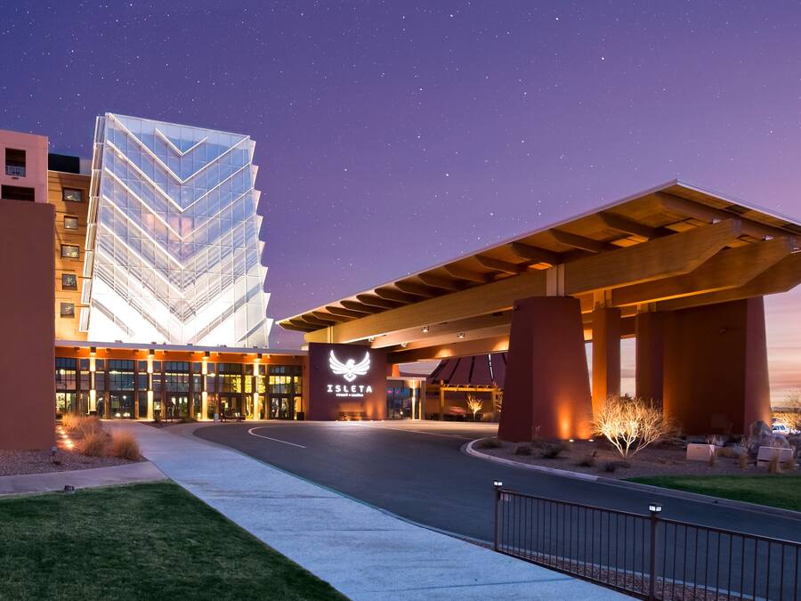 A hotel entrance with a modern building featuring a chevron pattern, a covered walkway, and a starry sky.