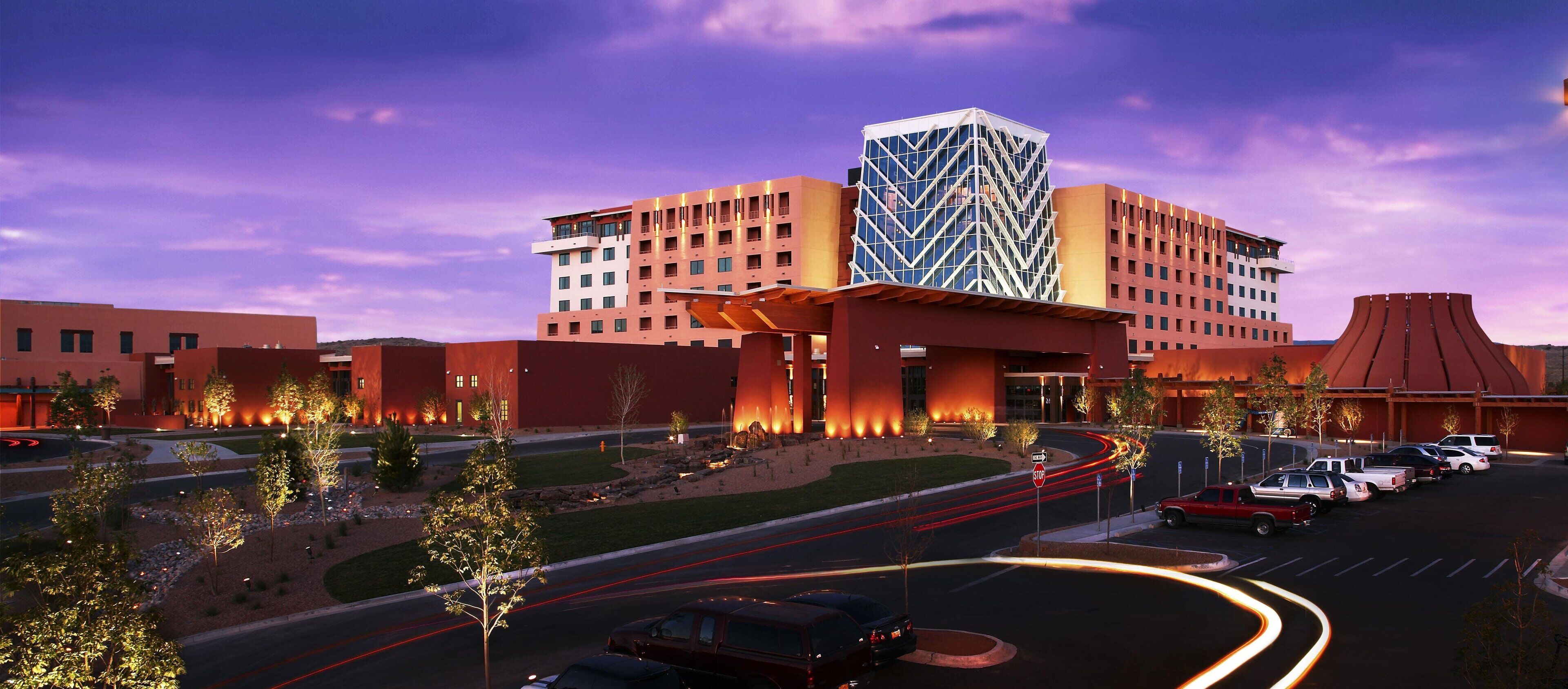 A modern hotel with a distinctive geometric facade, a landscaped courtyard, and a parking area with vehicles.