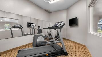 Une salle de sport équipée de tapis de course, d’un vélo d’appartement et d’un téléviseur fixé au mur.