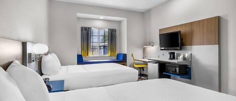 A hotel room with two beds, a desk with a chair, a television, and a window with curtains.