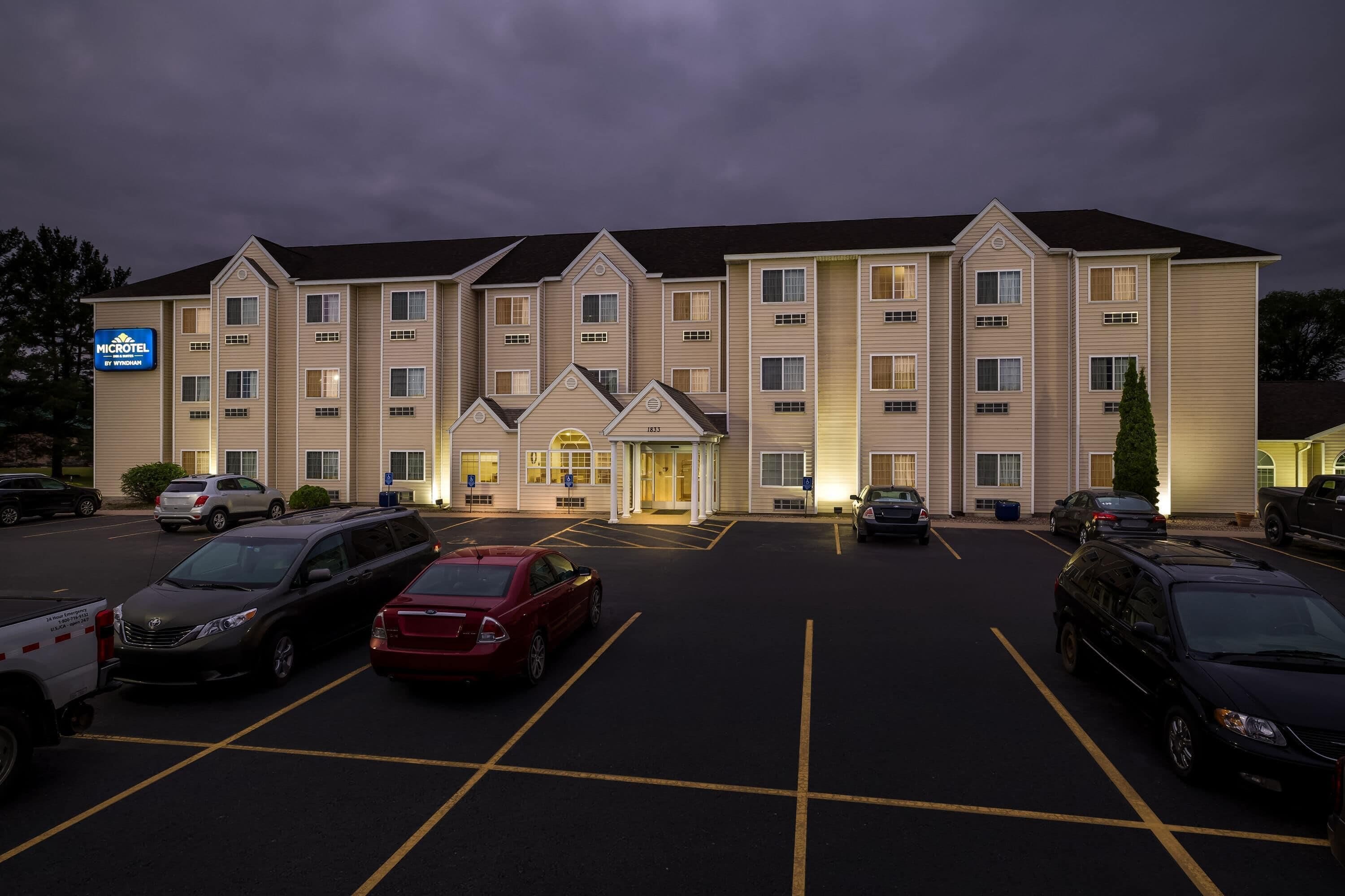 A multi-story hotel with a parking lot, marked parking spaces, and a sign indicating it is a Microtel hotel.