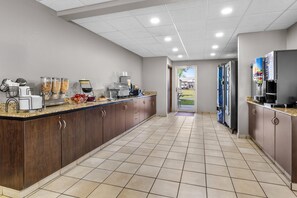 A modern kitchen with a long counter, coffee machines, and a view of the outdoors. - Microtel Inn & Suites by Wyndham Prairie du Chien (Prairie Du Chien)