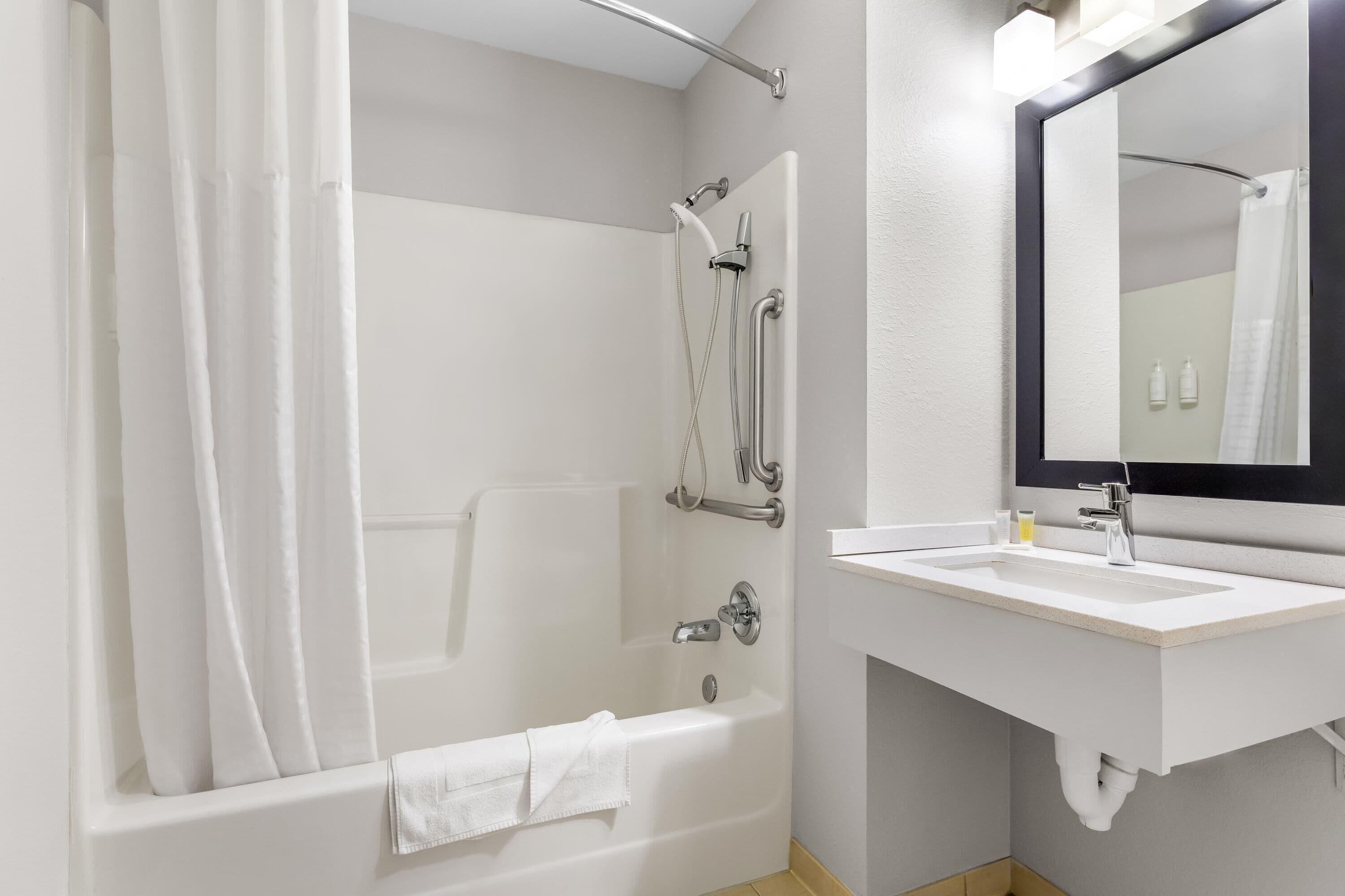 A modern bathroom with a bathtub, shower, and sink.