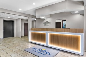 A reception area with a modern design, featuring a reception desk, a logo on the wall, and a tiled floor.