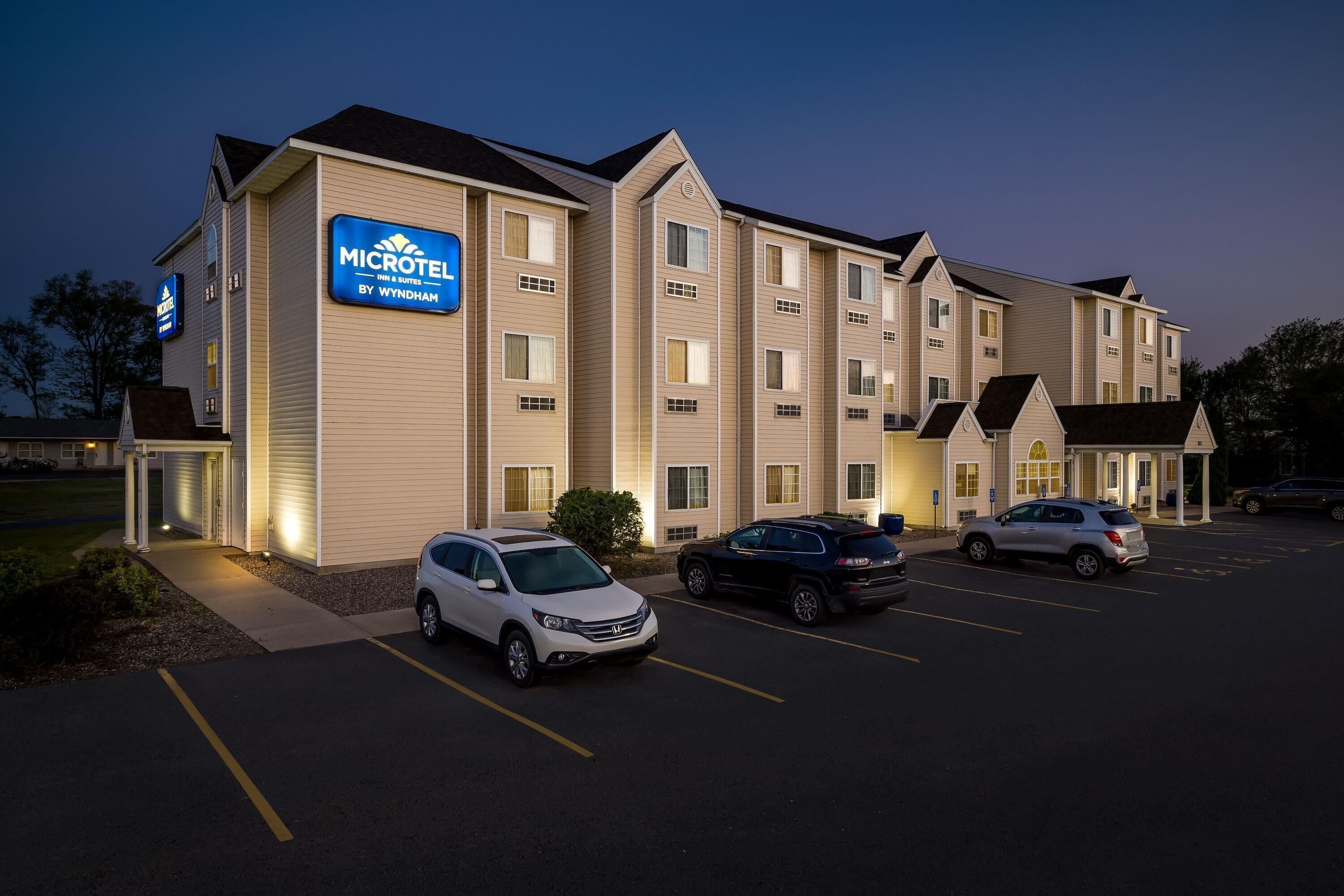 Ett Microtel-hotell som tillhör Wyndham-kedjan, med en parkeringsplats och flera fordon.