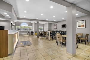 A hotel lobby with a reception desk, seating area, and large windows.