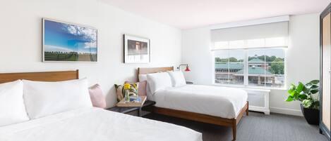Habitación de hotel con dos camas, ventana con vista a la ciudad y una planta.