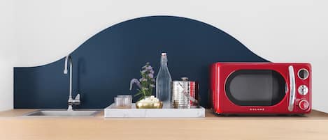 A kitchen counter with a red microwave, a bottle, and a small plant.