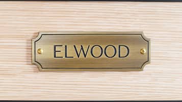 A brass nameplate with the word "ELWOOD" on a wooden surface.