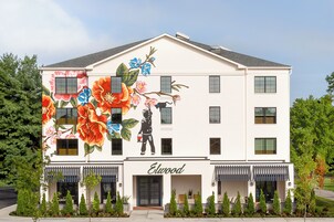Un edificio de dos pisos con fachada blanca y un gran mural floral en la pared.