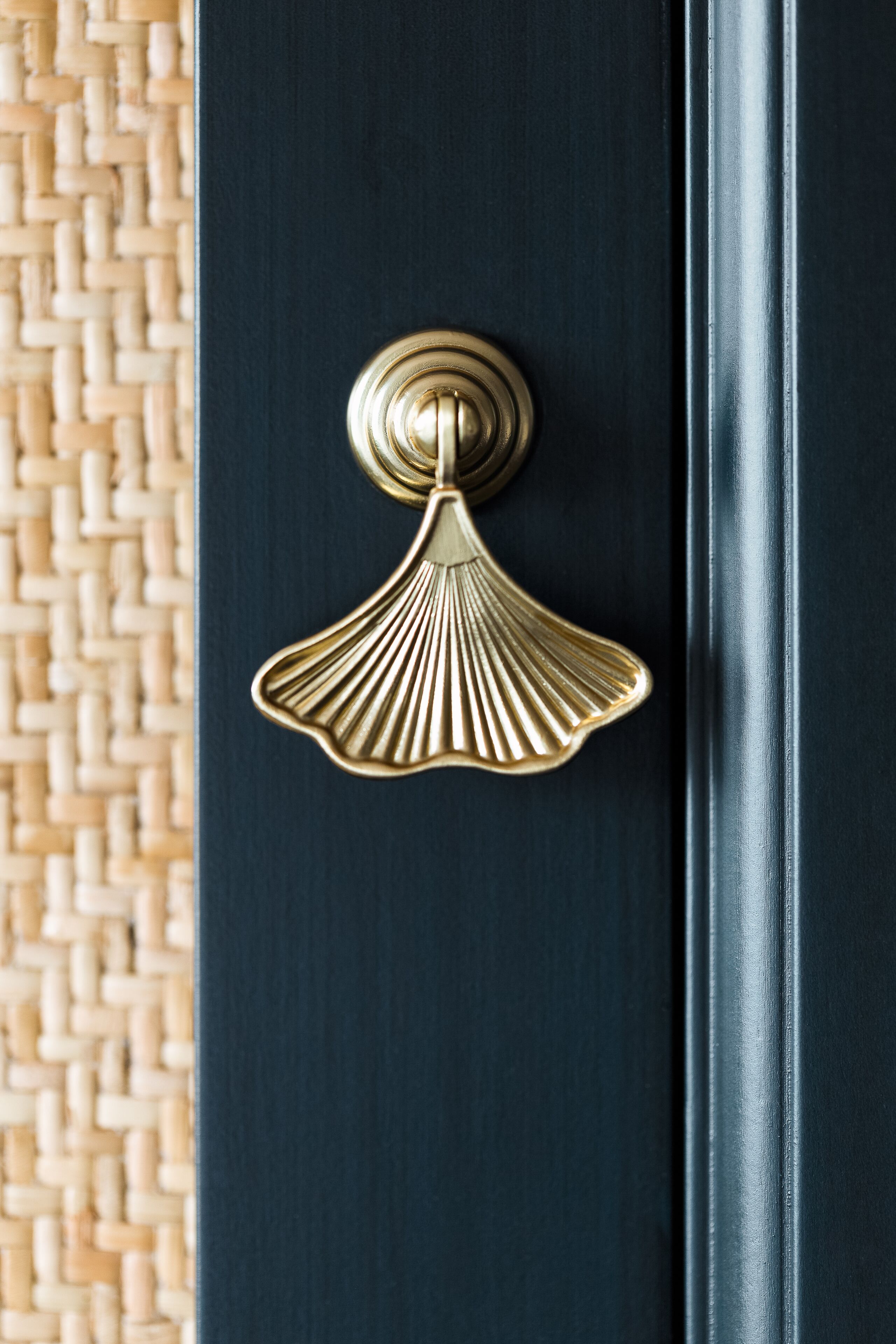 A close-up of a dark blue door with a gold-colored, scalloped handle.