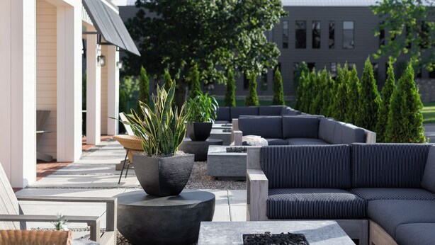 An outdoor seating area with modern furniture, planters, and a building in the background. - Elwood Hotel & Suites (Lexington)