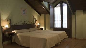 Una habitación con una cama, dos mesitas de noche con lámparas, un cuadro en la pared y una ventana con persianas.