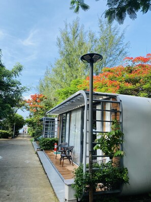 A modern, compact structure with a glass enclosure, a wooden deck, and a solar-powered lamp. - An Hoa Residence (Ho Chi Minh City)