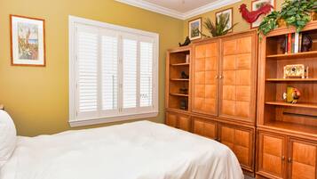 Cozy retreat with a large bed, wooden cabinet, and a window with white shutters.