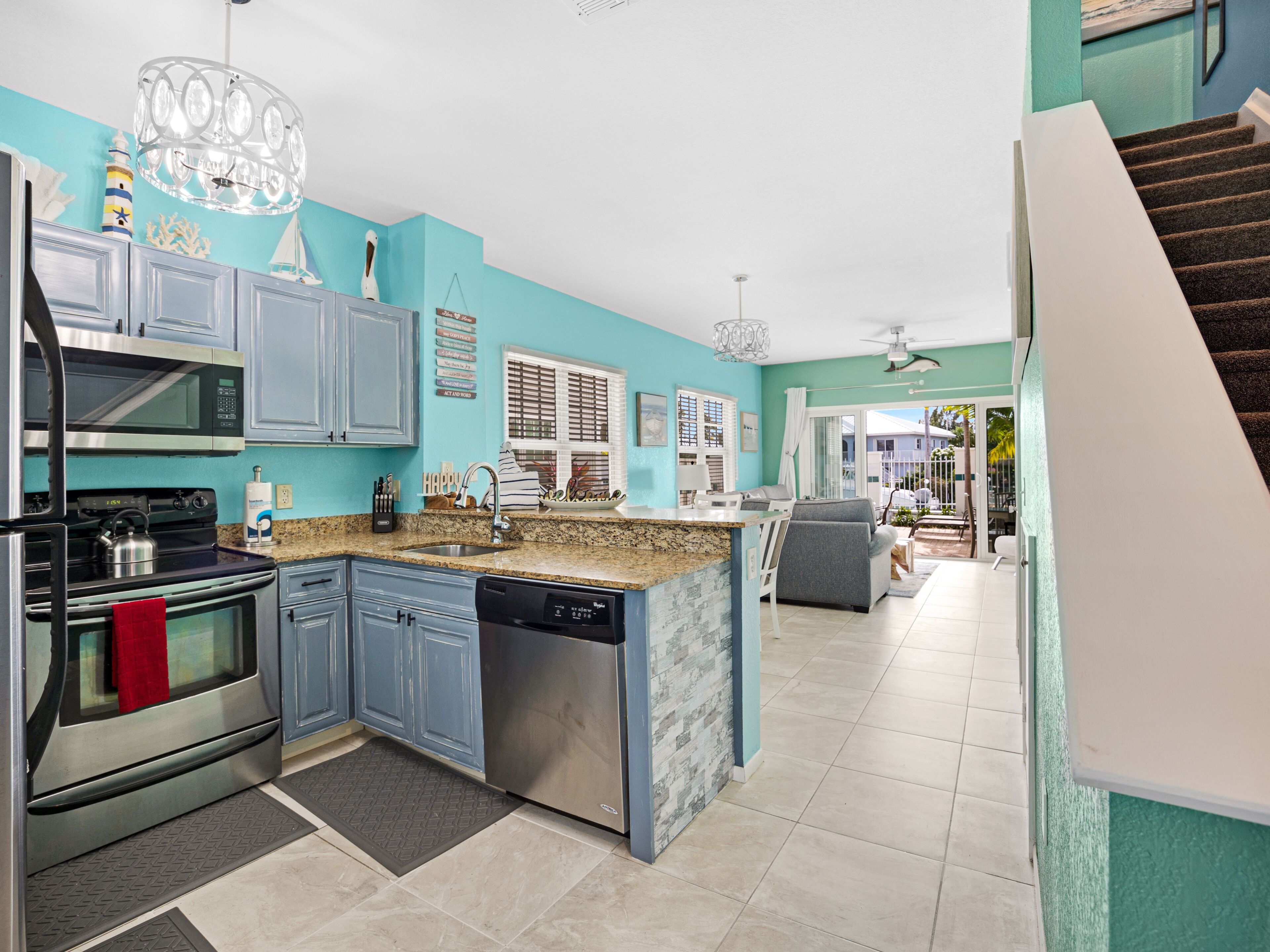 A modern kitchen with blue cabinets, stainless steel appliances, and a granite countertop.