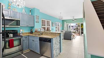 A modern kitchen with blue cabinets, stainless steel appliances, and a granite countertop.