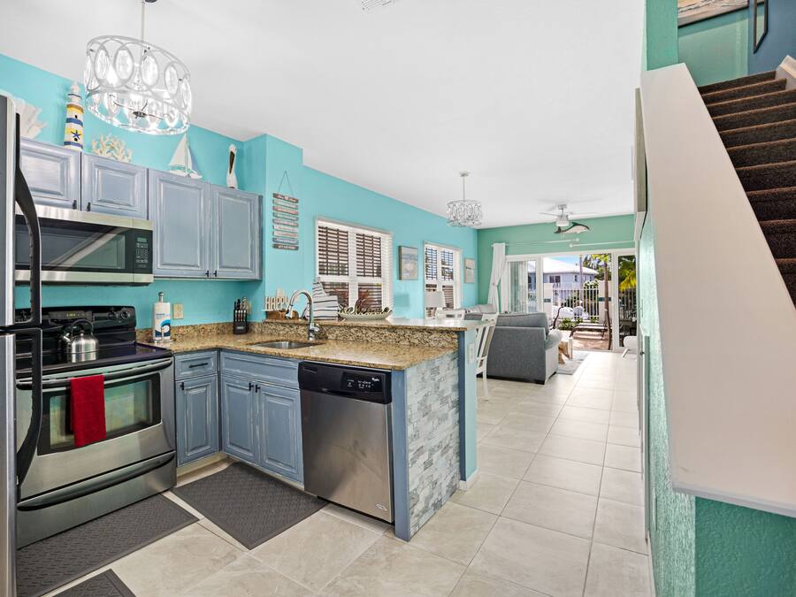 A modern kitchen with blue cabinets, stainless steel appliances, and a granite countertop.