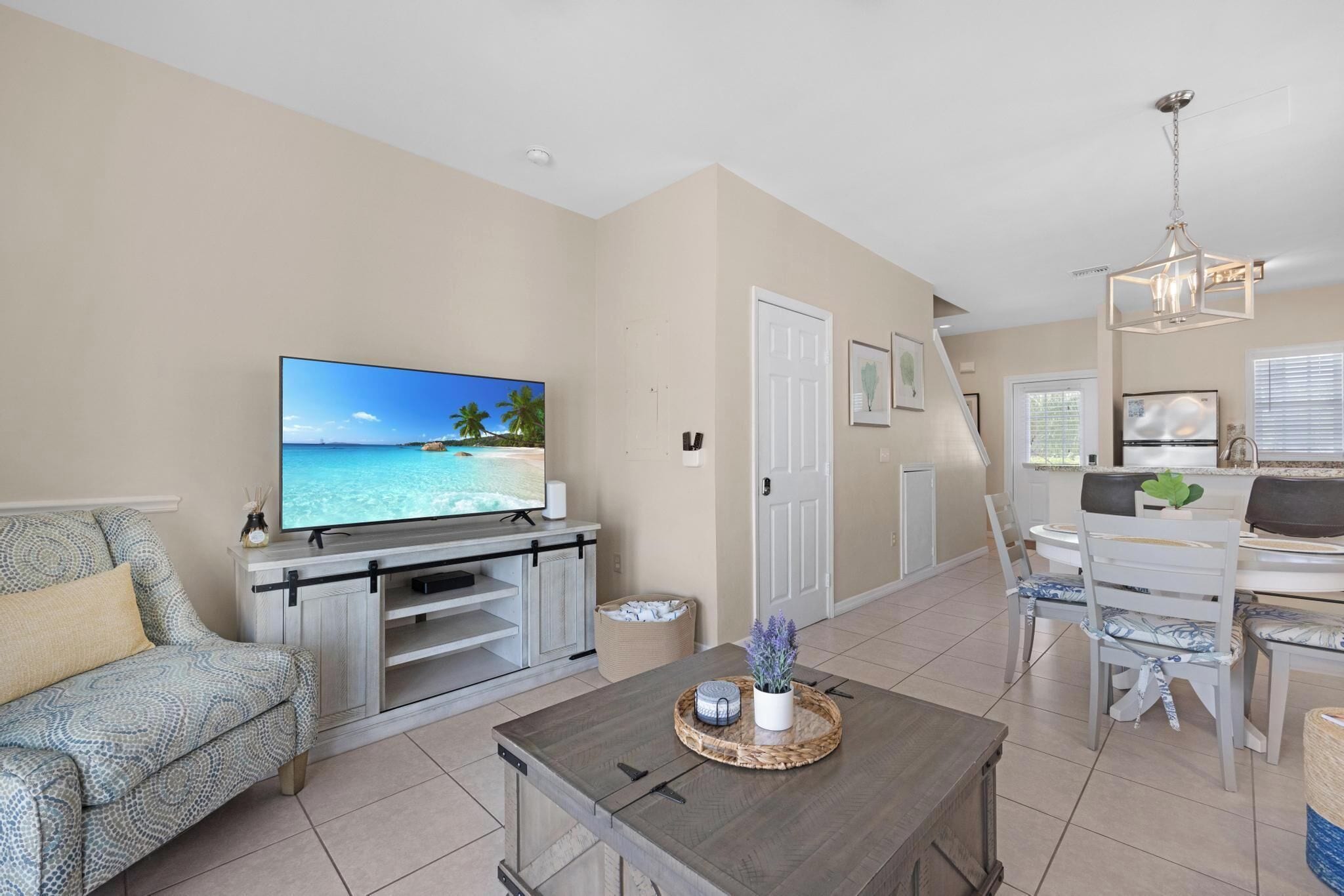 A living room with a flat-screen TV, a sofa, a coffee table, and a dining area with chairs and a table.