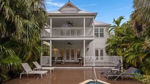 Ein zweistöckiges Haus mit Swimmingpool, umgeben von Palmen.
