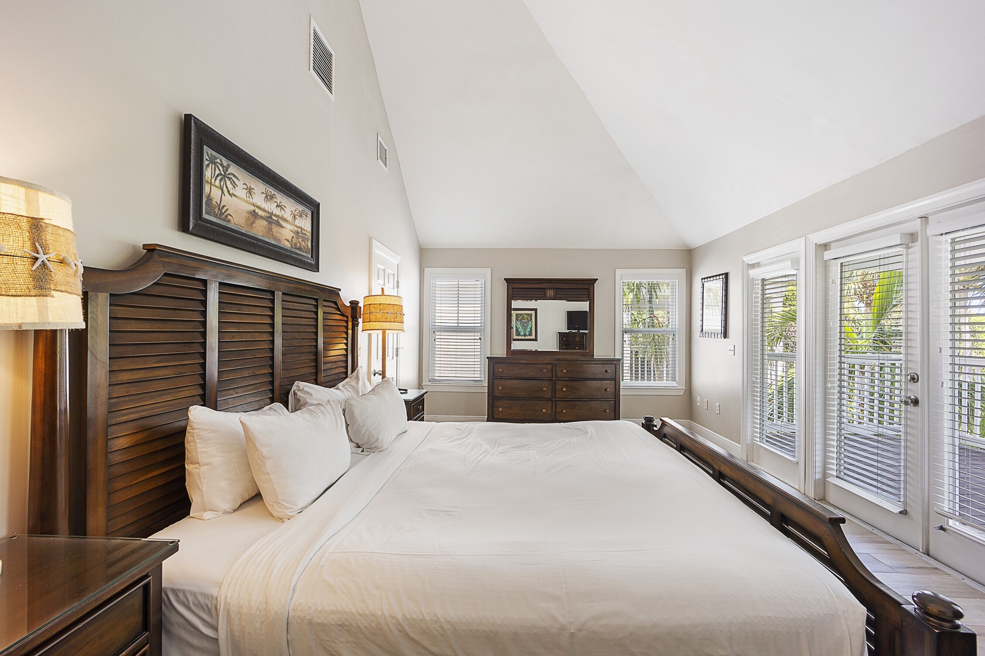 A spacious bedroom with a large bed, wooden headboard, and a dresser.