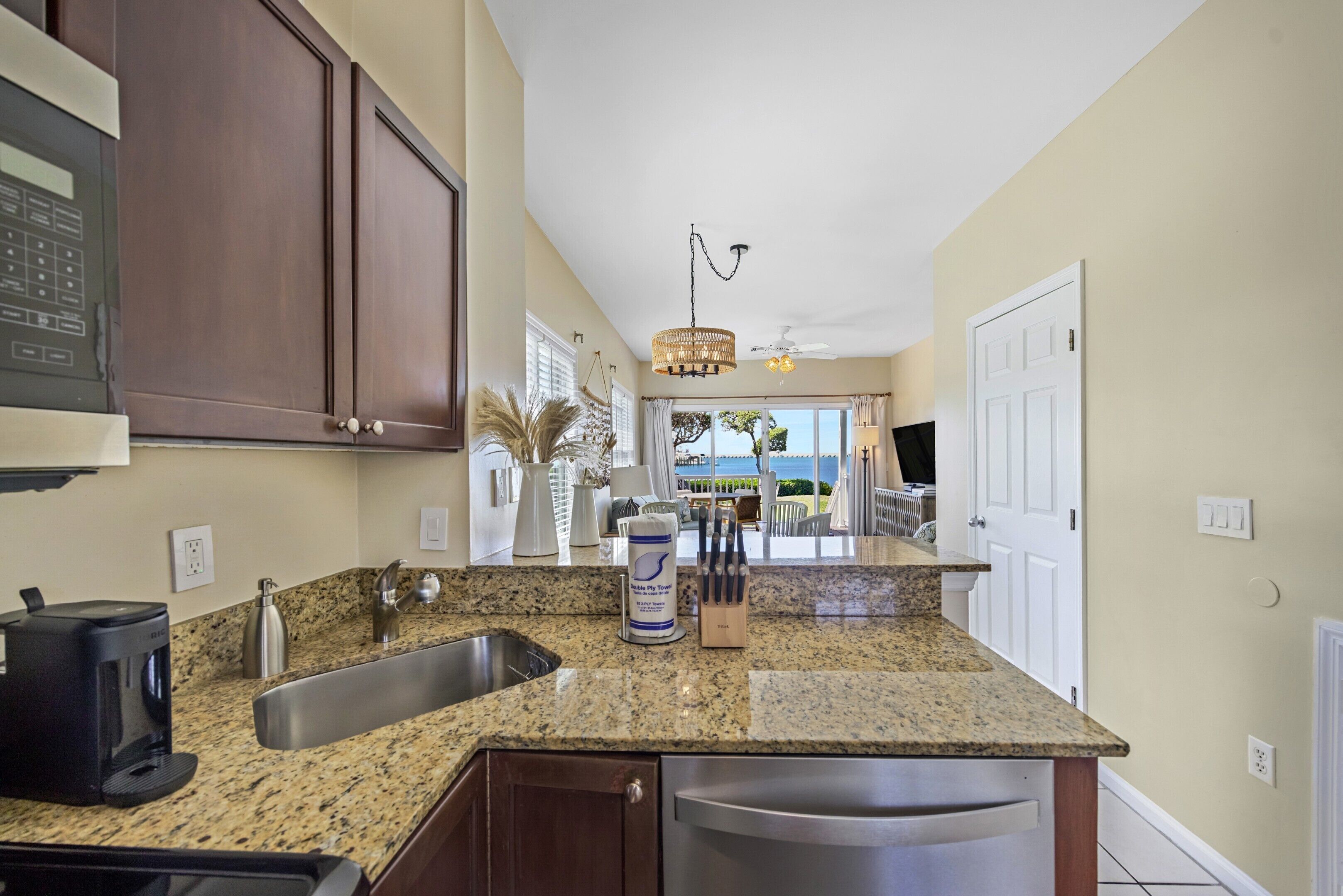 A kitchen with granite countertops, stainless steel appliances, and dark wooden cabinets.