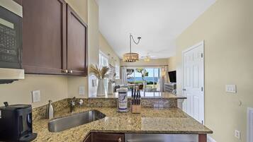 A kitchen with granite countertops, stainless steel appliances, and dark wooden cabinets.