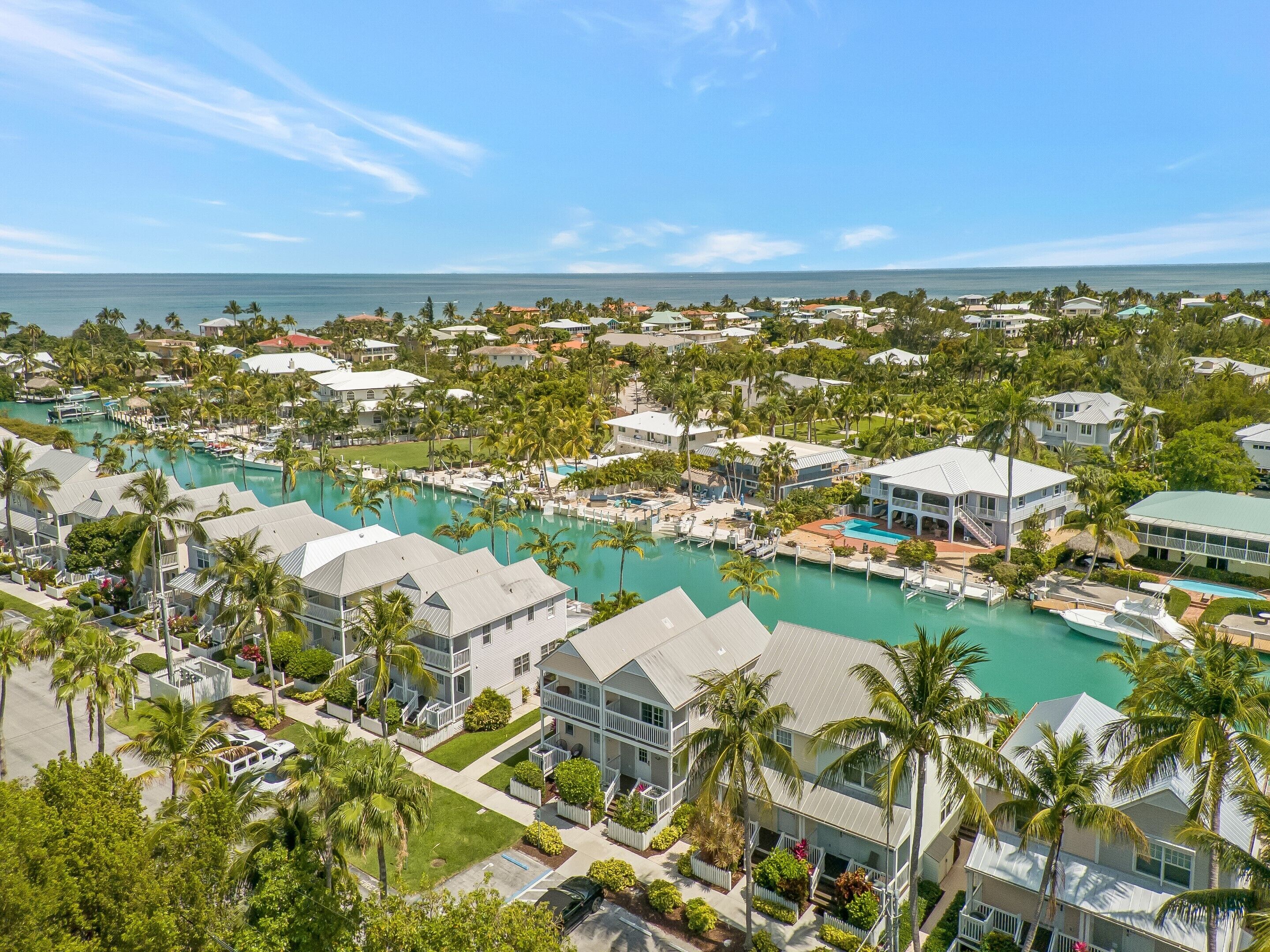 A coastal resort with multiple buildings, a marina, and a large turquoise pool.