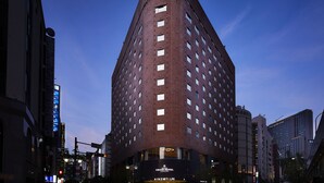 A modern hotel with a unique curved facade, multiple windows, and a prominent sign for the AINTZ TULPE hotel. - Ginza Grand Hotel (Tokyo)