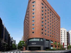 A multi-story building with a curved facade, featuring a prominent 'MAVEN' sign at the ground level. - Maven Ginza (Tokyo)