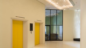 A modern interior with a high ceiling, yellow doors, and a unique light fixture. - Ginza Grand Hotel (Tokyo)