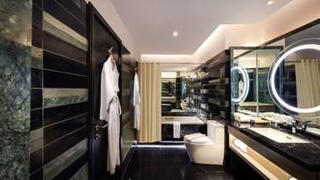 Un baño moderno con un espejo grande, baldosas de mármol negro y una bañera blanca.