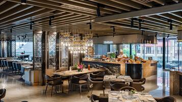 A modern restaurant with a wooden ceiling, a central bar area, and seating arrangements.